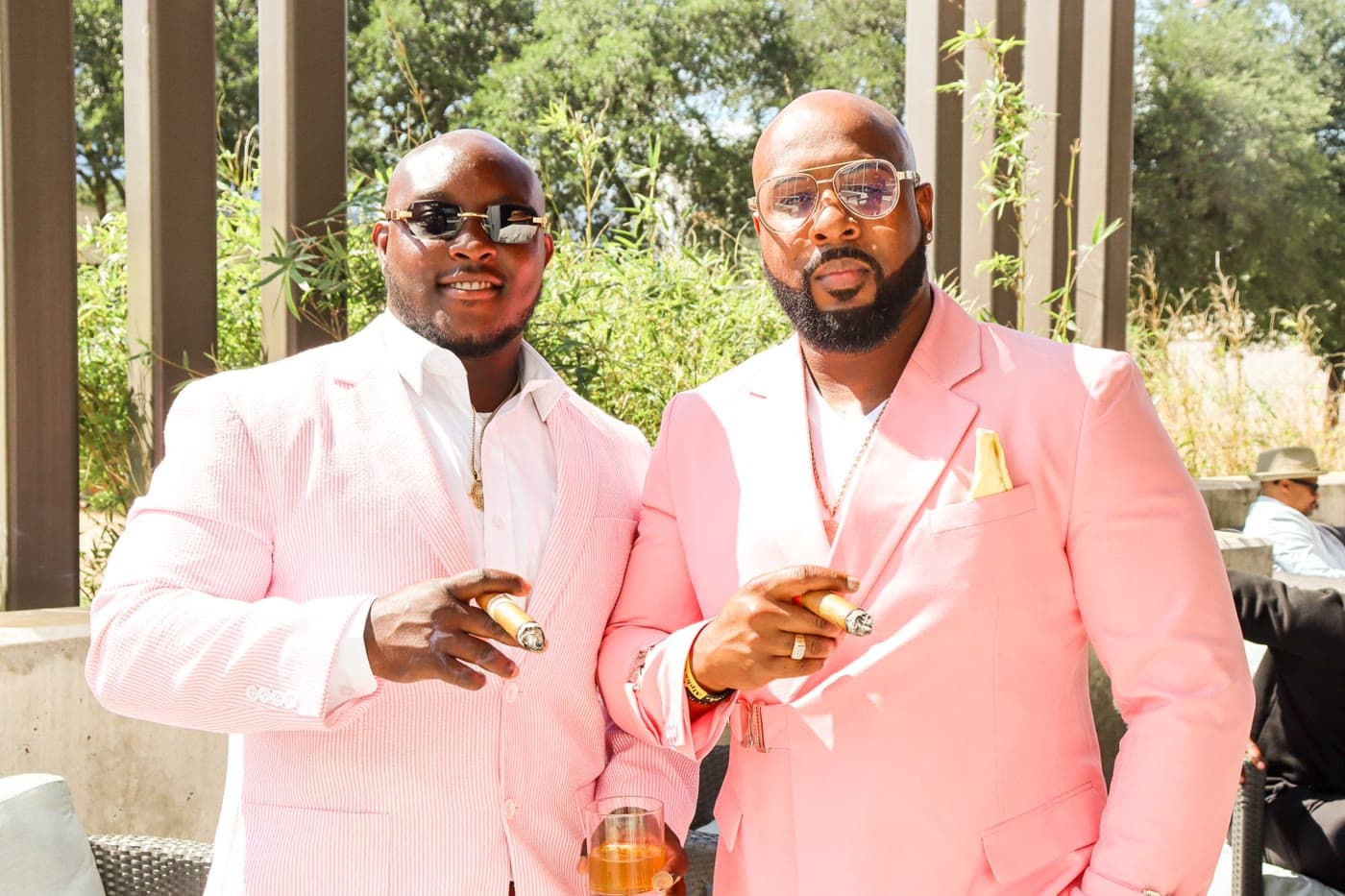 Two guests in pink tailoring with cigars in the outdoor lounge