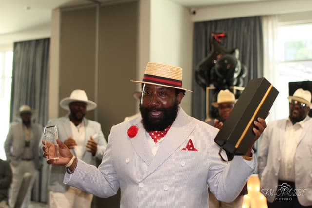 The Men's Best Dressed winner in a seersucker suit and straw boater, holding his trophy