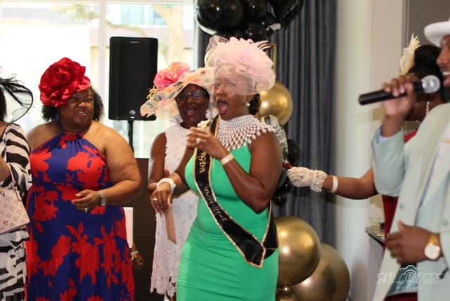 The Ladies' Best Hat winner in a pink fascinator and sash, celebrating on the floor